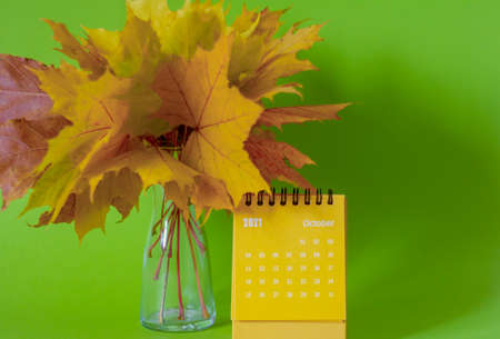 A tear-off calendar for October 2021 and an autumn bouquet of bright maple leaves. The concept of the Golden Autumnの写真素材