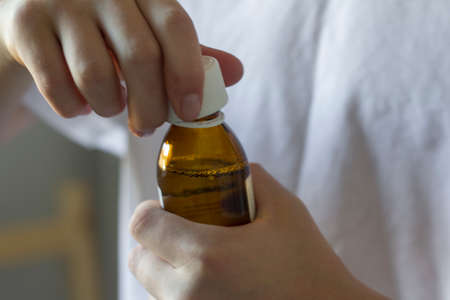 A young man holds a bottle of medicine in his hands to drinkの写真素材