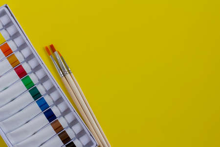 Bright acrylic paints in tubes and brushes for drawing on a yellow backgroundの写真素材