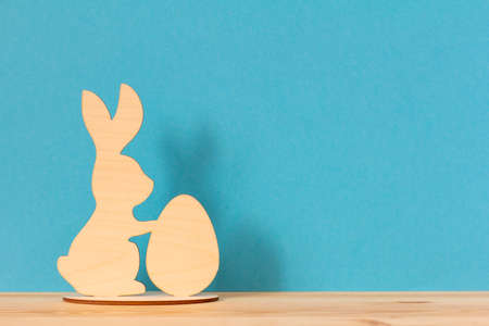 Easter wooden rabbit with an egg on a blue background