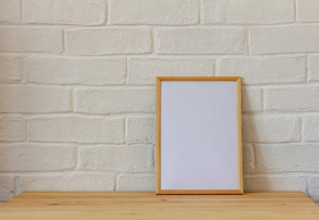 Empty photo frame in a wooden frame on a wooden table with copy space