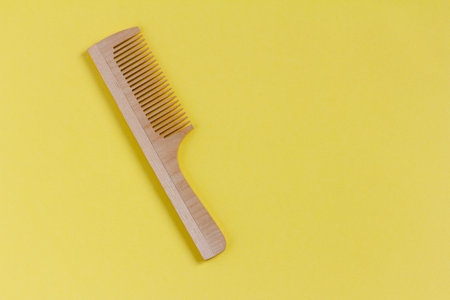 Wooden comb on a yellow background, top viewの写真素材