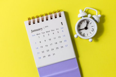 January 2024.Desk calendar for 2024 and alarm clock on a lilac backgroundの写真素材