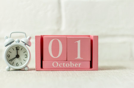 October 1 on the wooden calendar next to the alarm clock is the start date of the new monthの写真素材