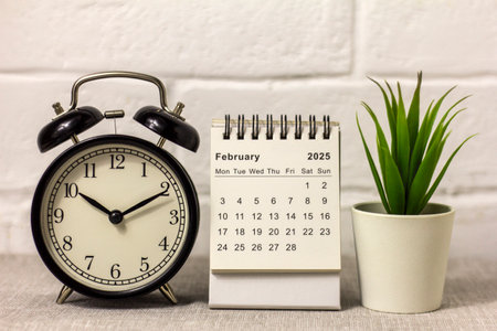 Desk calendar for February 2025 and clock on the tableの写真素材