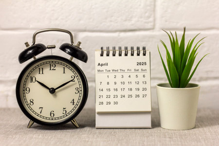 Alarm clock and desk calendar for April 2025 for planning on your desktopの写真素材