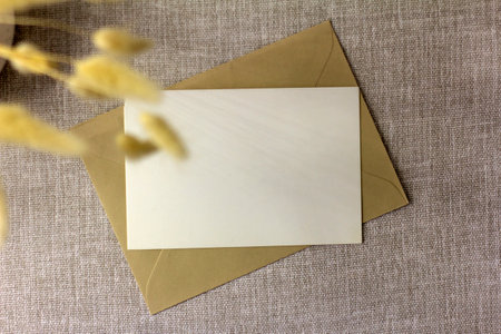 Blank horizontal postcard or invitation mockup. Envelope on beige or gray table background. Copy spaceの写真素材