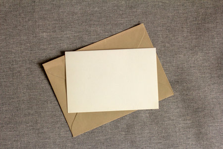 Blank horizontal postcard or invitation mockup. Envelope on beige or gray table background. Copy spaceの写真素材