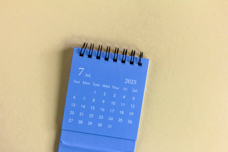 Hello, July 2025. Desktop calendar for planning on a beige background with copy space