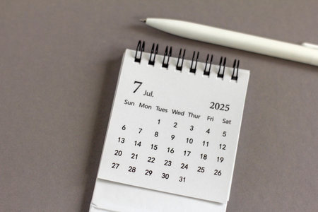 A desktop calendar for July 2025 on a desk with space to copy
