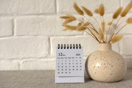 A calendar for December 2025 and a bouquet of dried flowers on the table