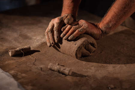 Hands of the potter knead clay. Kneads crude clay on a tableの写真素材