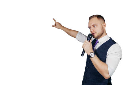 Young elegant talking man holding microphone talking with pointing finger. Isolated on white background. Showman conceptの写真素材
