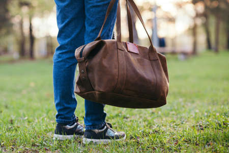 The girl with a leather bag outdoors.の写真素材