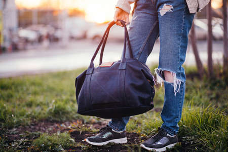The girl with a leather bag against the background of cars.の写真素材
