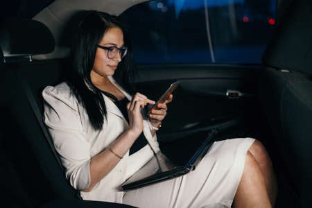 Beautiful business woman sitting in back seat of carの写真素材