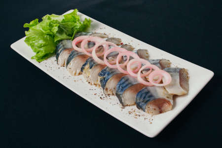 Sliced herring with herbs and onion. white plate, black background.の写真素材