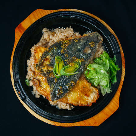 Fried rice with deep-fried spicy fish on a wooden board close up
