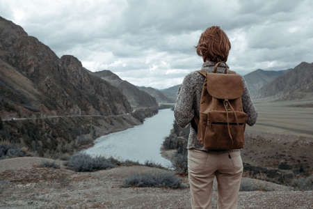 Hipster young girl with backpack enjoying sunset on peak of foggy mountain. Altaiの写真素材