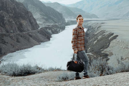 Man with bag in hand walking down a mountain road