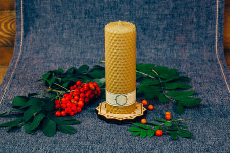 Christmas wax candle. Not burning candle, a mountain ash. A wooden background with fabric.の写真素材