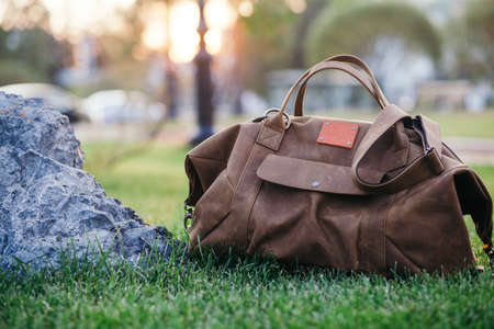 Retro brown shoes and man leather bag in bright colorful summer grass in the park