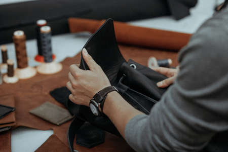 The master makes a leather bag. A close up, a product from skin in hands. Handwork