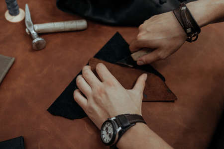 Close-up. Male hand master cut with a knife to skin products. Small business.の写真素材