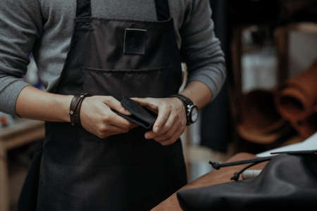 Close-up. The master in production of products from skin holds in ruky a purse