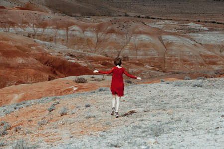 Woman stands in the beauty of red valley. She wears a beautiful red dress. Romantic.の写真素材