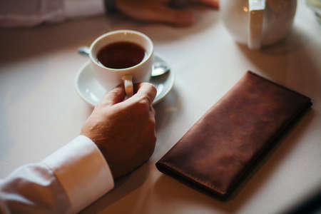 The businessman has coffee in cafe. Nearby the purse lies