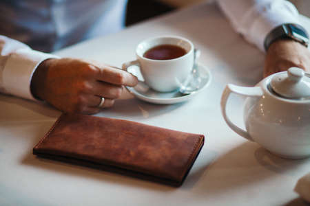 The businessman has coffee in cafe. Nearby the purse liesの写真素材