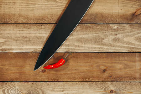 Red pepper with a knife on a wooden backgroundの写真素材