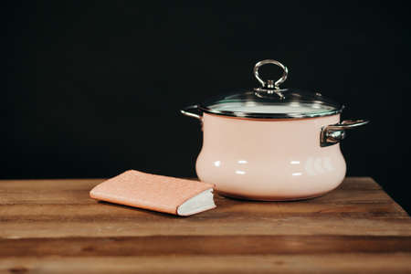 Vintage style pink enamel saucepan on wooden background