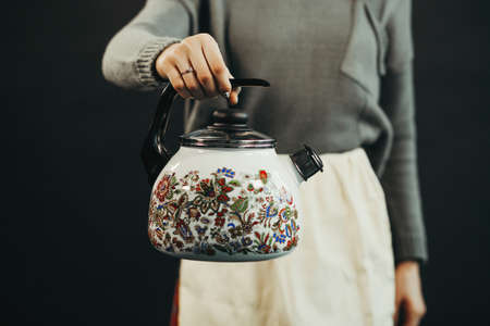 Woman hand holding kettle on a black backgroundの写真素材