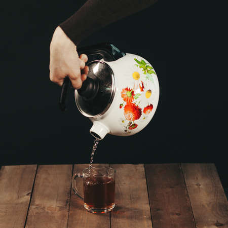 Process brewing tea,tea ceremony,Cup of freshly brewed black tea,warm soft light, darker background