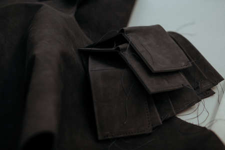 Black leather wallets and pieces of black leather on a table in a workshop