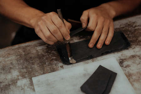 Close up of master making leather wallet with brush and glue. Handmade master at work in local...