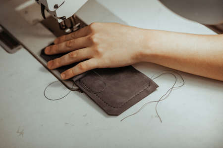 Close up of sewing machine working part with leather. The masters hands sews a leather product. Handmade concept.の写真素材