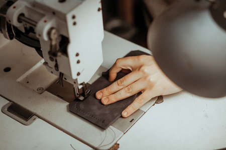 Close up of sewing machine working part with leather. The masters hands sews a leather product. Handmade concept.の写真素材