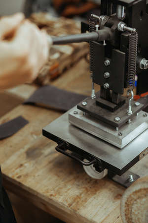 Press machine in the workshop for doing the embossed logo and letters on the leather product that heats the cliche and squeezes the desired image on the materialの写真素材