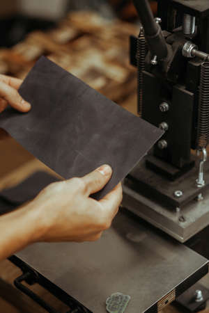 Man holding leather craft and working. Press machine in the workshop for doing the embossed logo and...