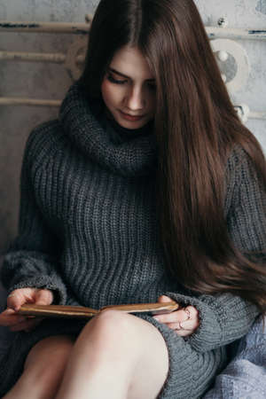 Beautiful woman at home sitting on a bed reading a book.の写真素材