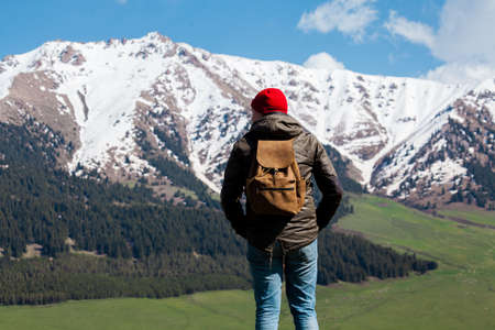 Man with backpack standing in field at the mountains