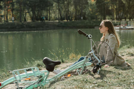 Girl sitting near by lake in autumn park