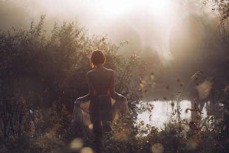 Young half-naked woman standing in tall grass
