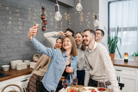 A team of happy young people pose together for a selfie group photo near the holiday table.の写真素材