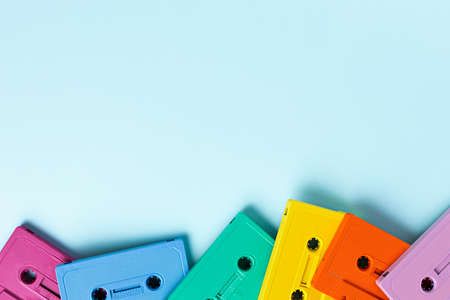 Retro cassette tapes at the bottom of the photography on a bright blue background. Minimalist art photography inspired by summer colors and music. Cassette tapes in rainbow colors.の写真素材