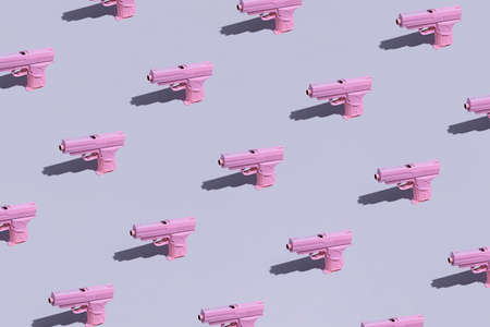Pink-colored pistols pattern on a pale lilac background. Pistol toys overload. Pink guns on a monochrome lavender background.の写真素材