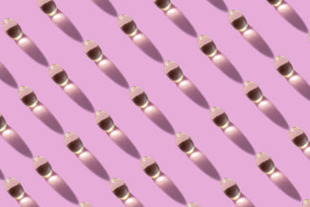 Creative layout of pills and capsules on pink background with summer sun and sharp shadow.の写真素材